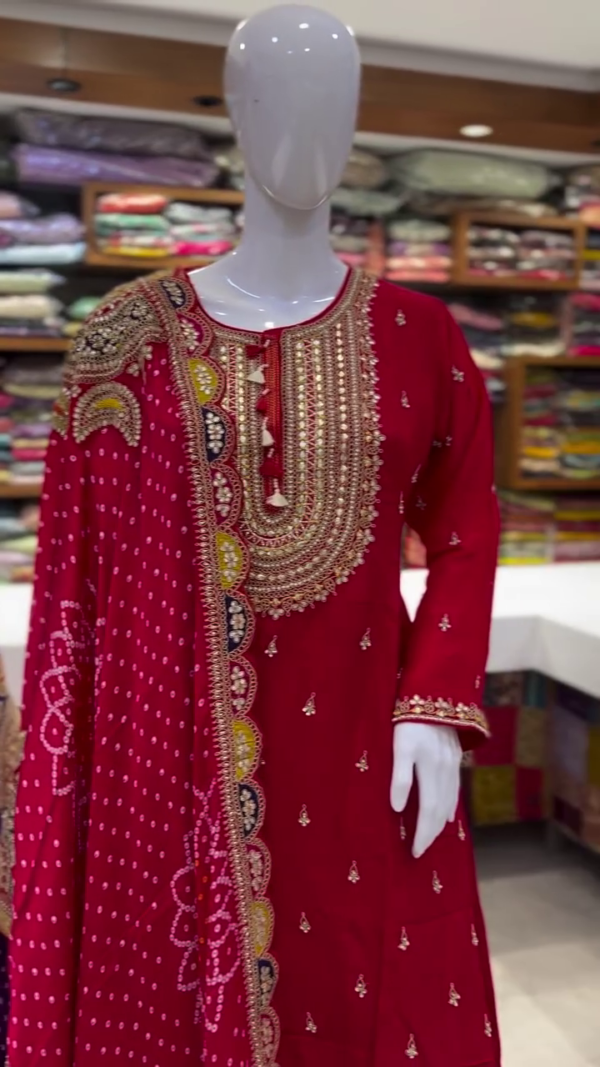 Regal Dual Sharara Suit Set Featuring Rich Purple and Vibrant Red Variants, Both Adorned with Intricate Golden Embroidery on Neckline and Sleeves, Paired with Flowy Tiered Shararas and Traditional Bandhej-Inspired Dupattas Accentuated with Gota Patti Borders and Festive Motifs – A Perfect Blend of Heritage Craft and Celebration Charm - Image 2
