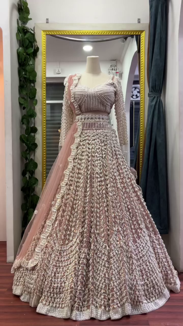 Luxurious Dusty Rose Pink Heavily Embellished Bridal Lehenga Choli Set Featuring Intricate Silver Zari and Sequin Embroidery, Full-Sleeve Pearl-Studded Blouse, and Scallop-Edged Net Dupatta – A Grand Ensemble for Weddings and Regal Celebrations