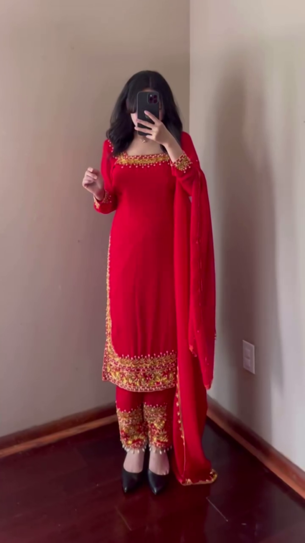 A stunning red ethnic outfit with intricate golden embroidery along the neckline, sleeves, and pant hems. The ensemble is complemented by a matching dupatta