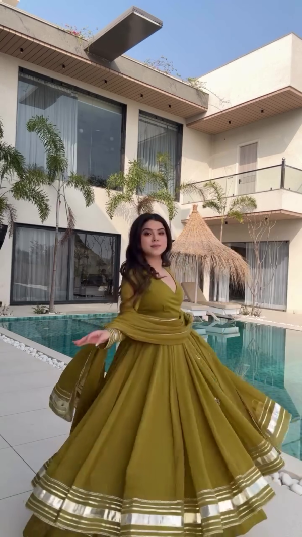 Radiating Elegance in a Beautiful Olive Green Anarkali Dress with Gold Detailing, Twirling Gracefully by the Poolside in a Stunning Modern Outdoor Setting - Image 2