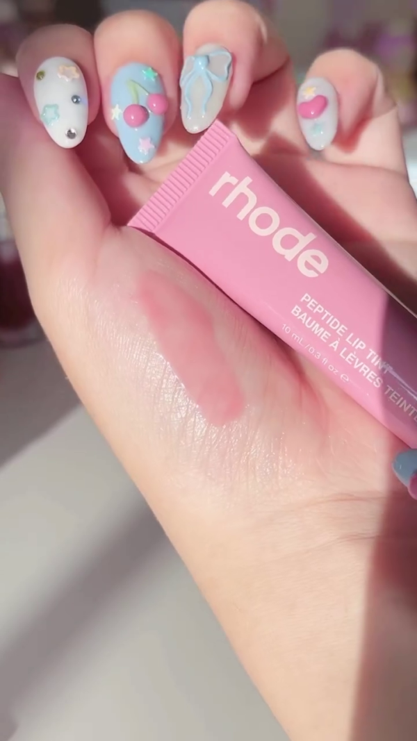 A pretty pink lip tint from Rhode, giving a soft, natural flush of color with a glossy finish. The packaging is simple yet sleek, and the product offers a light, buildable tint perfect for a subtle lip look. - Image 2
