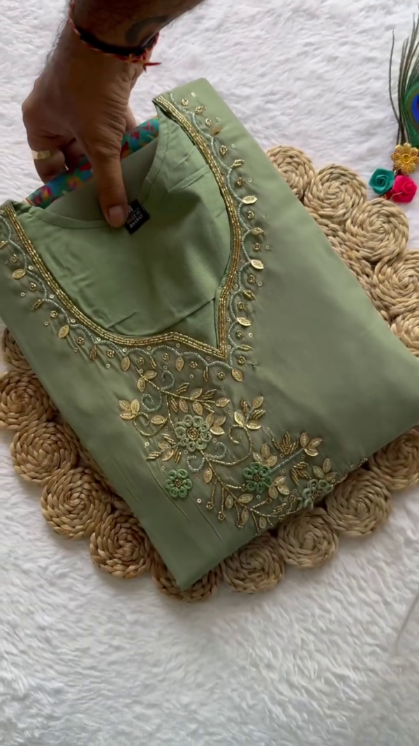 A graceful sage green ethnic set featuring a rich satin finish with golden embroidery on the neckline. Paired with a coordinating dupatta that showcases delicate motifs and a shimmering border — ideal for festive gatherings or elegant day functions.