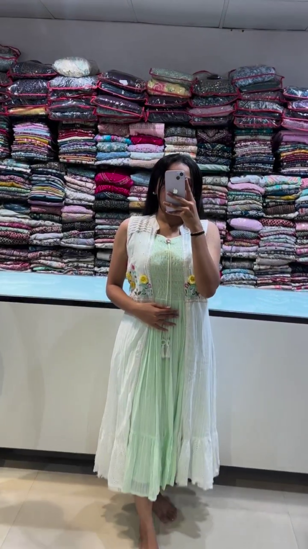 A breezy pastel green sleeveless dress layered with a white embroidered jacket, featuring delicate floral threadwork. Perfect for casual summer outings or festive day events with a touch of charm and comfort.
