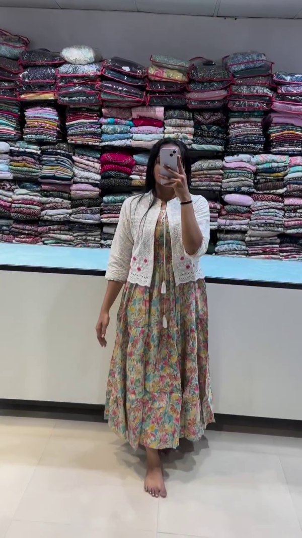 A floral multicolored maxi dress paired with a cropped white embroidered jacket adorned with pink threadwork. A vibrant, cheerful look ideal for brunch dates, festive gatherings, or casual daywear with a boho twist.