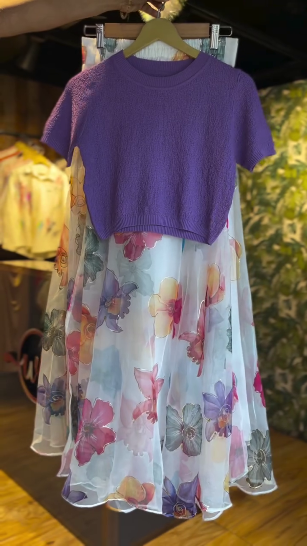 Chic Layered Dress – Soft Purple Short-Sleeve Knit Top Over a Flowing White Sheer Skirt with Vibrant Multicolor Floral Prints for a Playful and Elegant Look