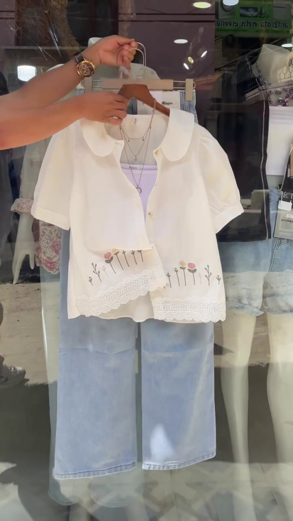 Casual Chic Outfit – Cream Short-Sleeve Button-Up Shirt with Peter Pan Collar, Lace Hem, and Delicate Floral Embroidery, Layered Over a White Inner Top, Paired with Light Blue Wide-Leg Jeans for a Fresh, Relaxed Look